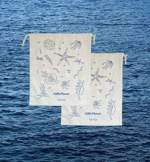 Two white drawstring bags with ocean-themed designs on a blue water background