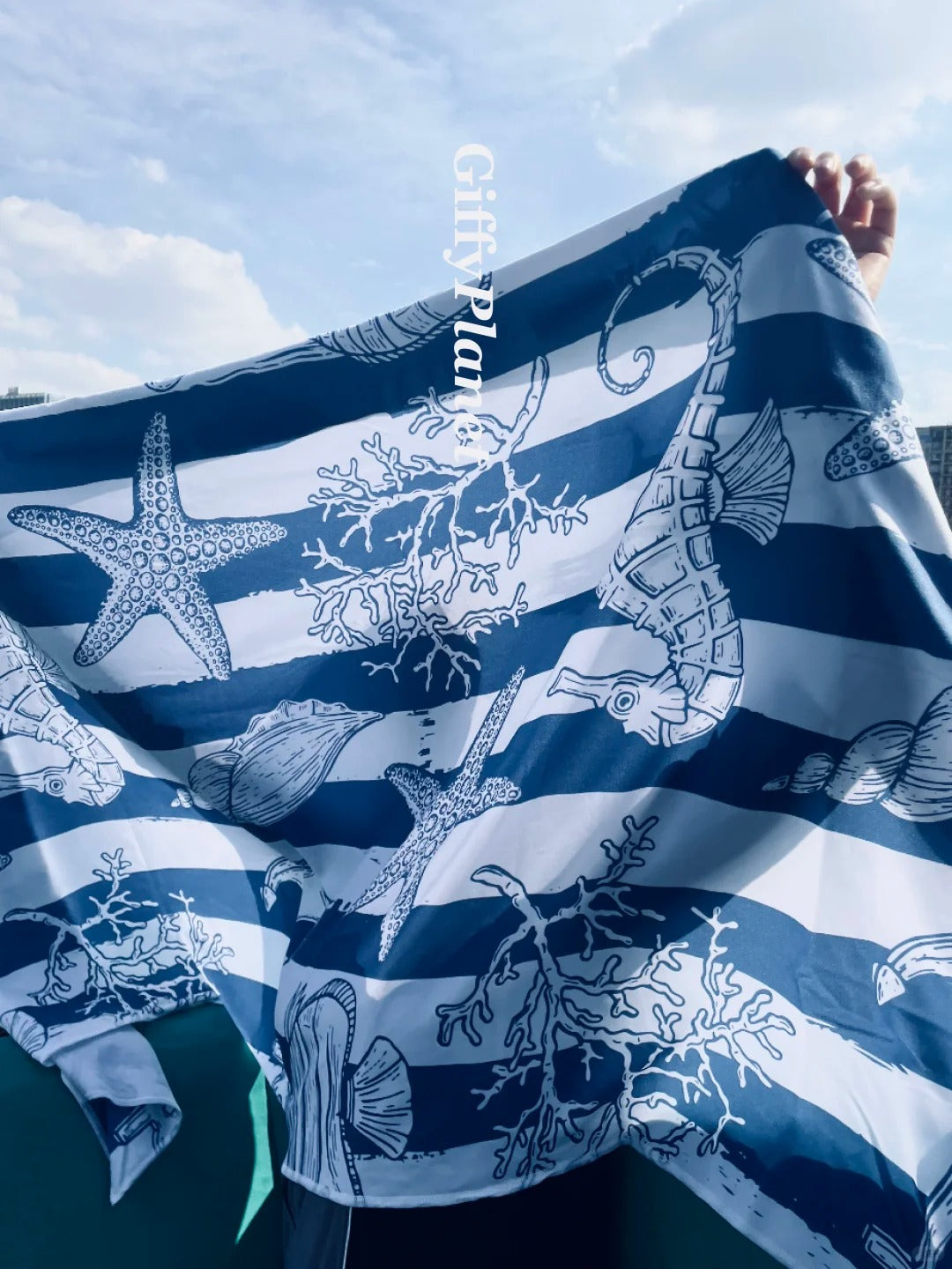Nautical-themed fabric with seahorse, starfish, and coral design on a blue and white striped background.
